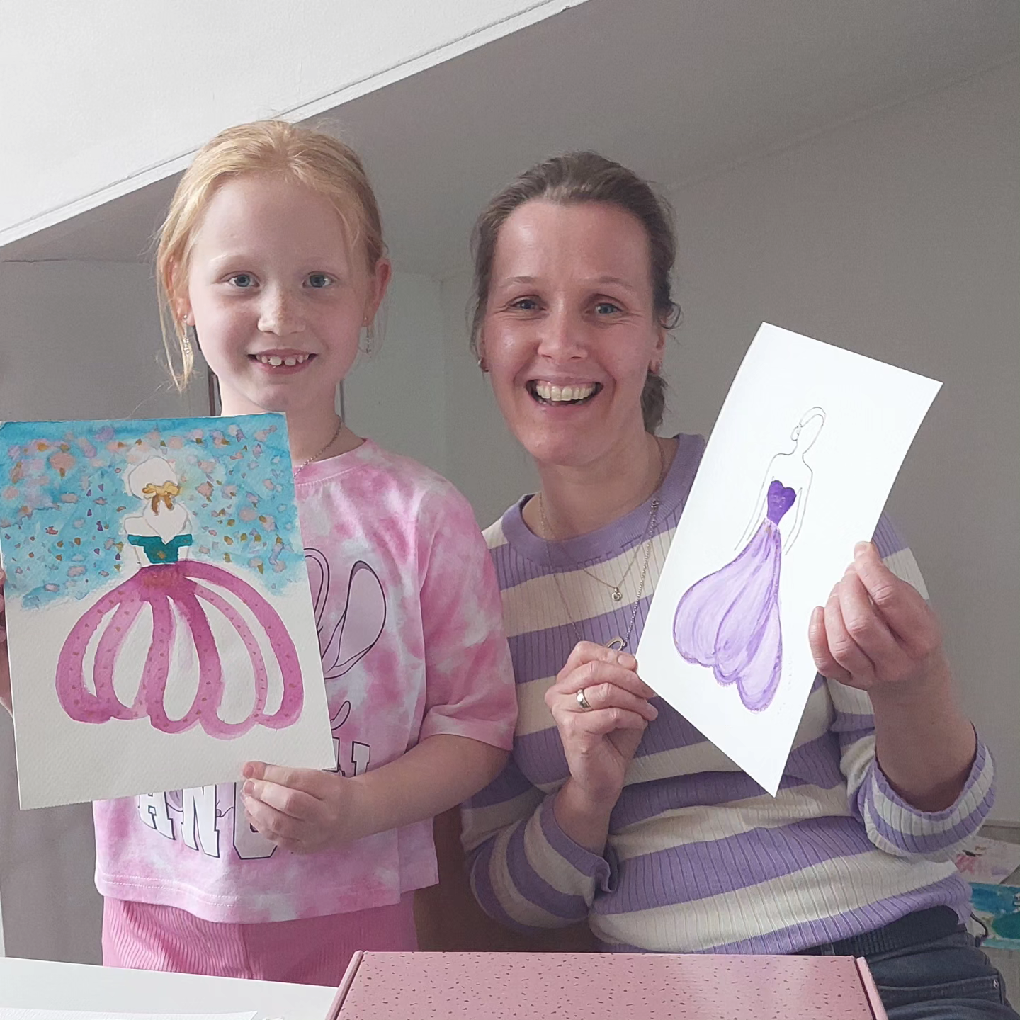 Twee deelnemers van de workshop: Aquarel de basis, hoe werkt aquarellen. Ze laten het eindresultaat zien wat ze hebben geschilderd. Twee kleurige illustraties.